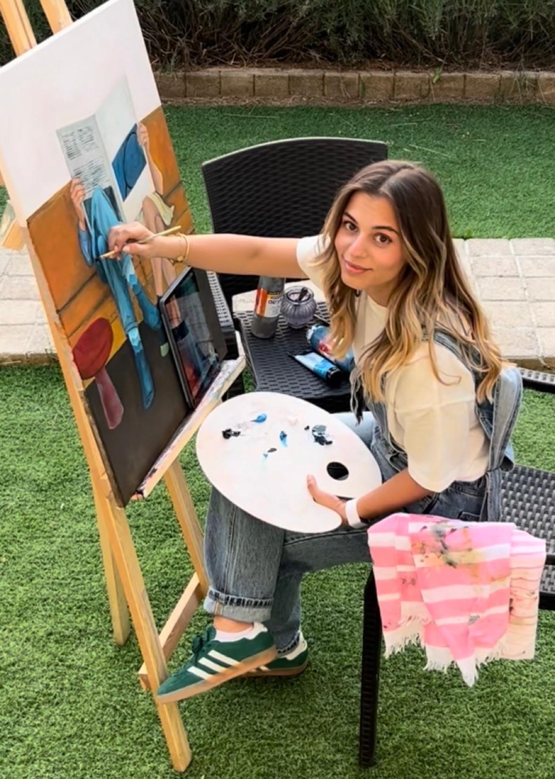 Myriam painting at an easel, palette in hand