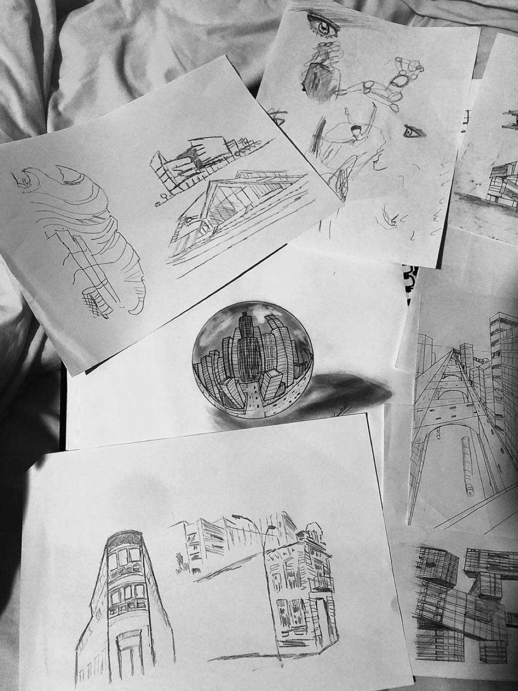 Pencil sketches of buildings and cityscapes spread on a bed