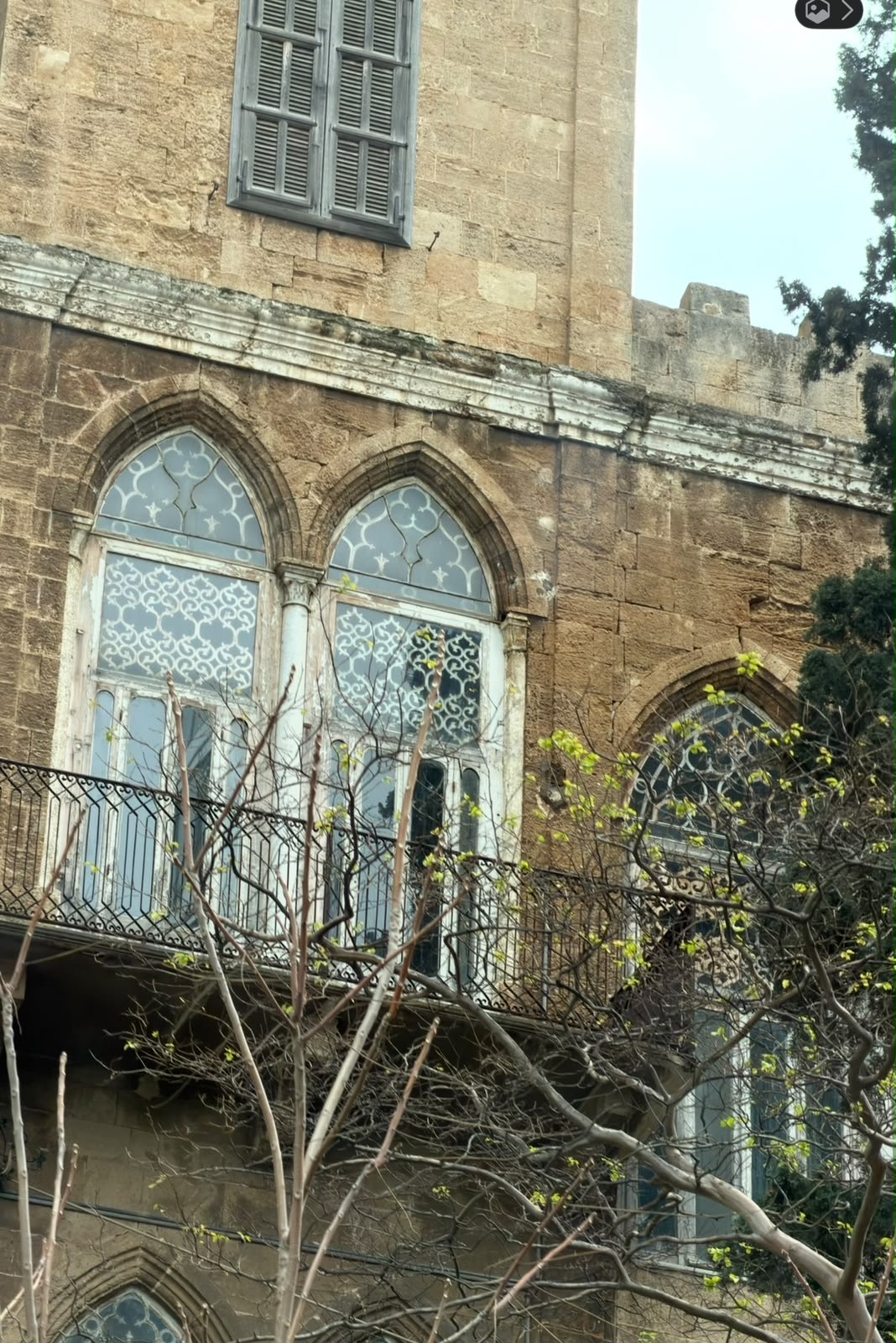 Old Beirut house with arched windows and a tree budding with new leaves